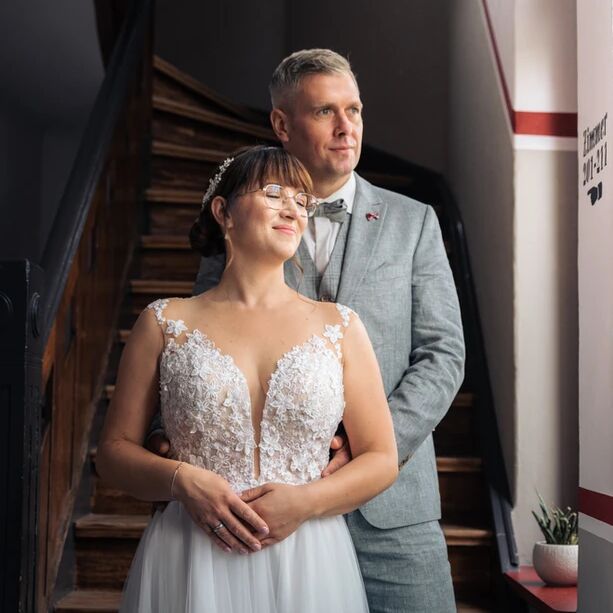 Brautpaar am Hochzeitstag vor einer alten Holztreppe stehend