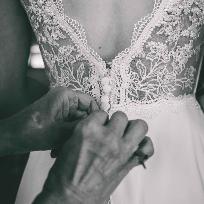 Anziehen des Brautkleides mit schönem Rückenausschnitt während des Getting Ready's für eine Hochzeit in Leipzig