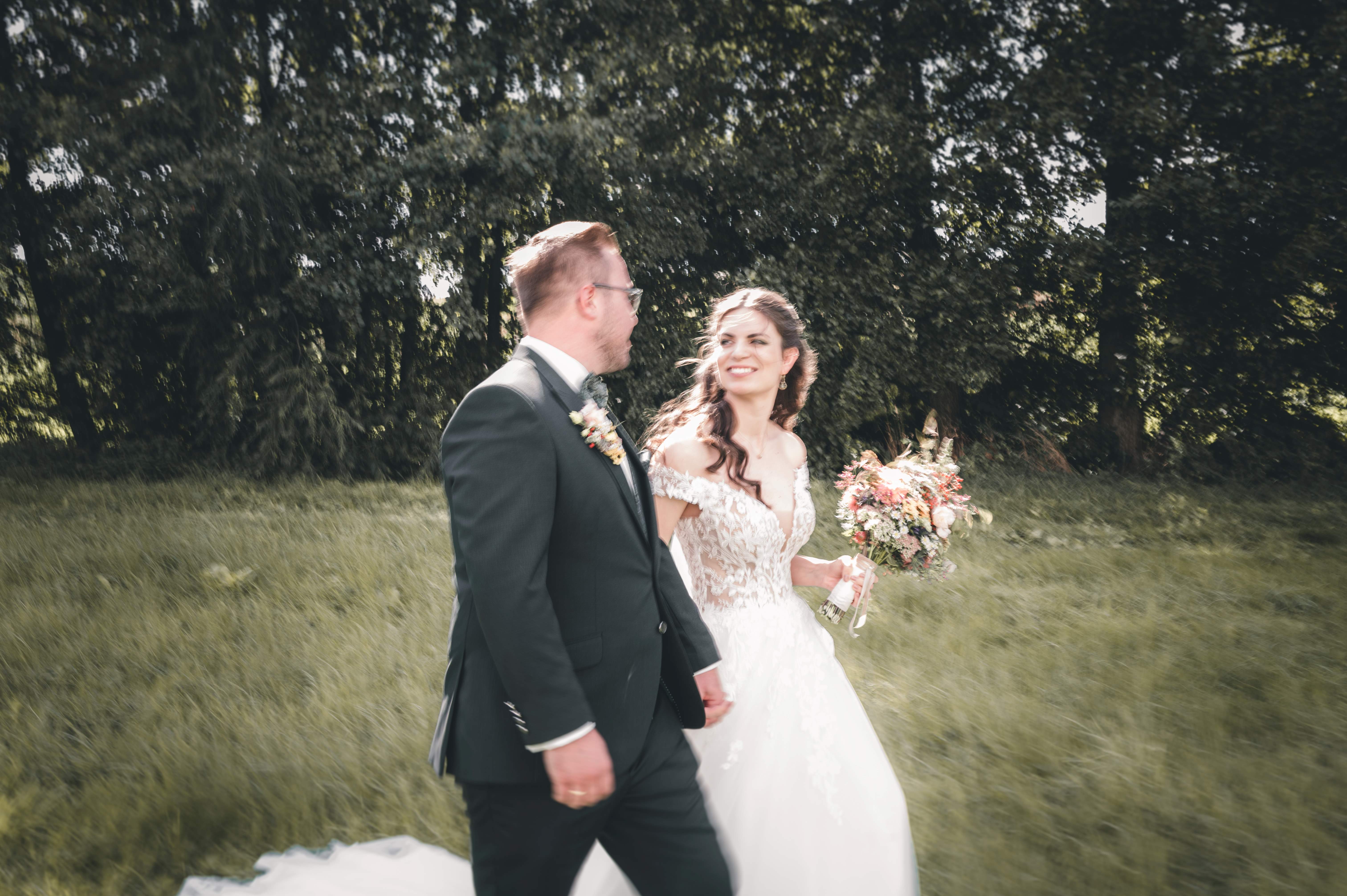 Brautpaar läuft über eine Wiese nach der kirchlichen Trauung in Leisnig während eines natürlichen Brautpaarshootings