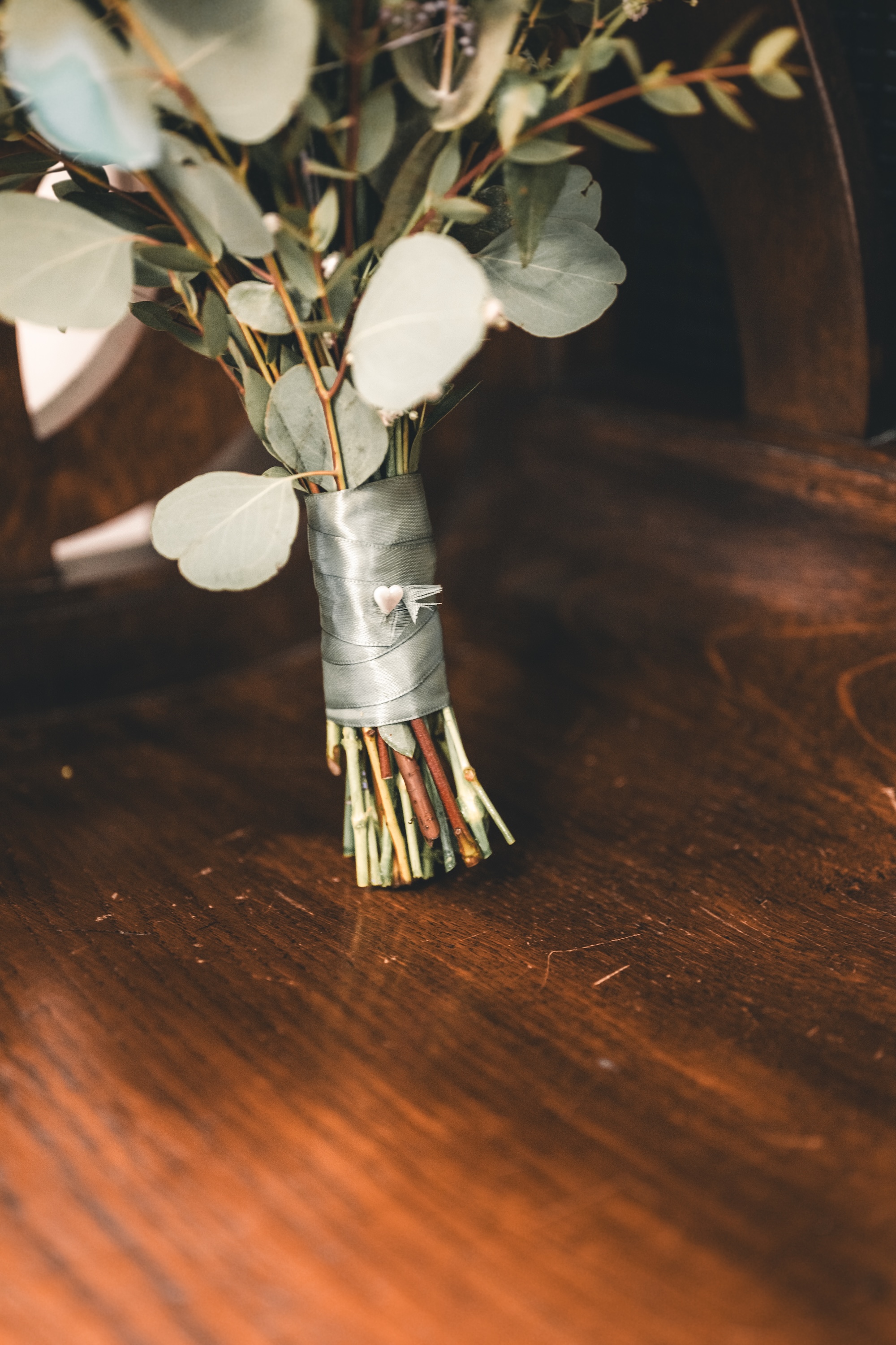 Detailaufnahme eines natürlichen Brautstraußes mit Eukalyptus auf Holzoberfläche – Hochzeitsreportage Leipzig