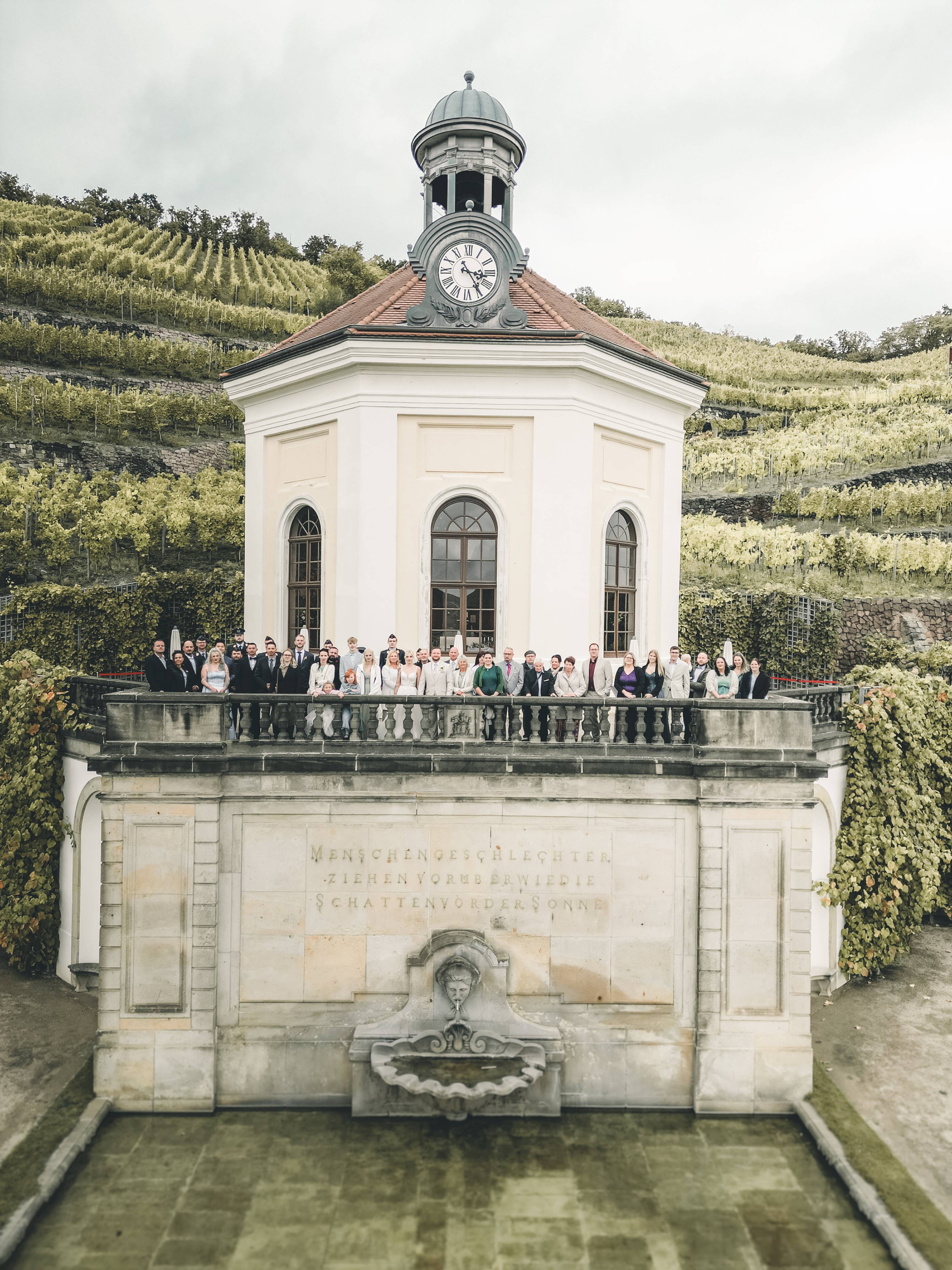 Drohnenfoto mit Hochzeitsgesellschaft auf dem Balkon der Kapelle auf Schloss Wackerbarth in Radebeul bei Dresden, hochzeitsfotografin aus Leipzig für lebedige und einzigartige Hochzeitsfotos