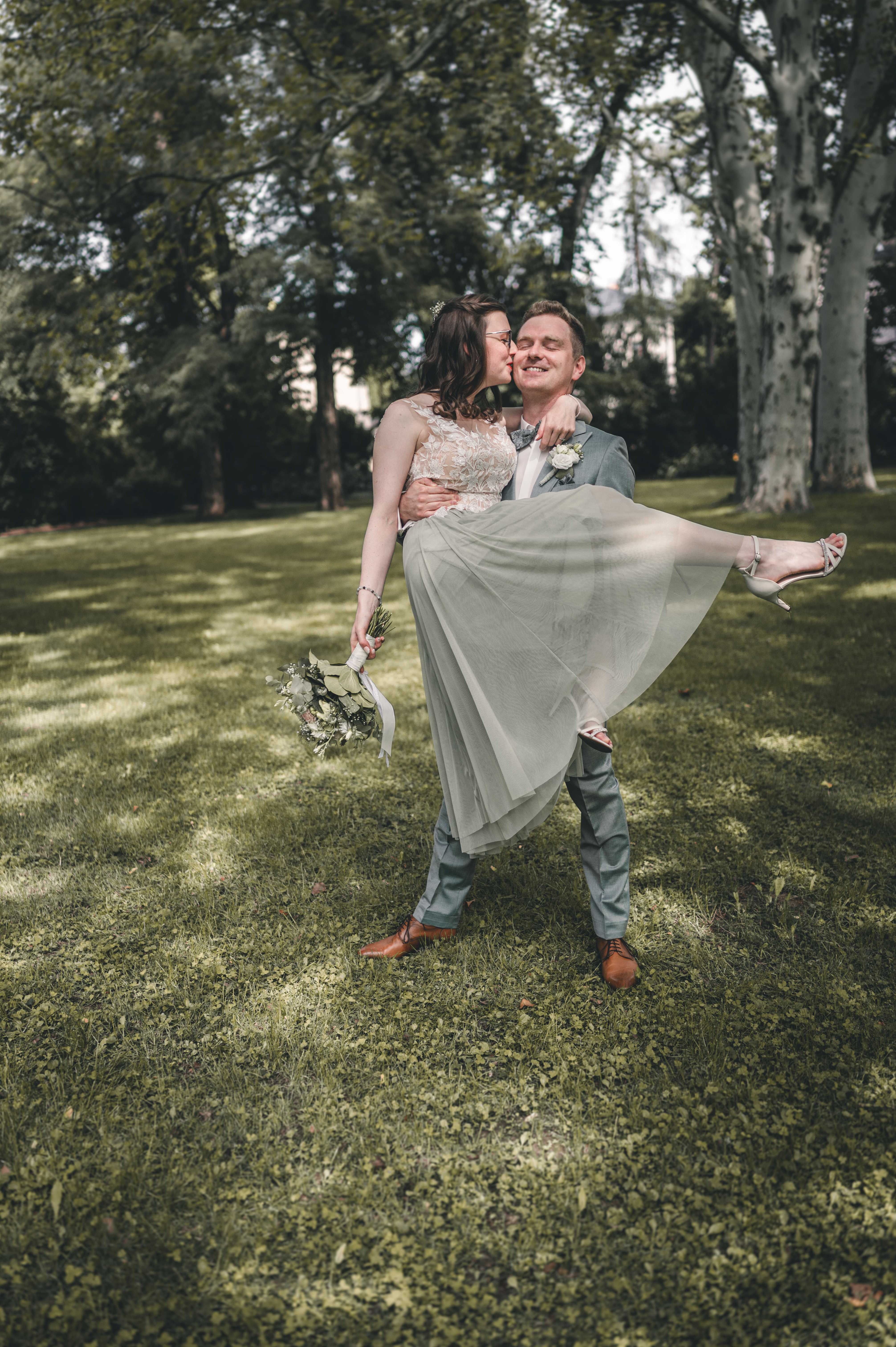 Bräutigam trägt seine Braut im Park vor der standesamtlichen Trauung in Altenburg – romantisches Brautpaarshooting einer Hochzeitsreportage