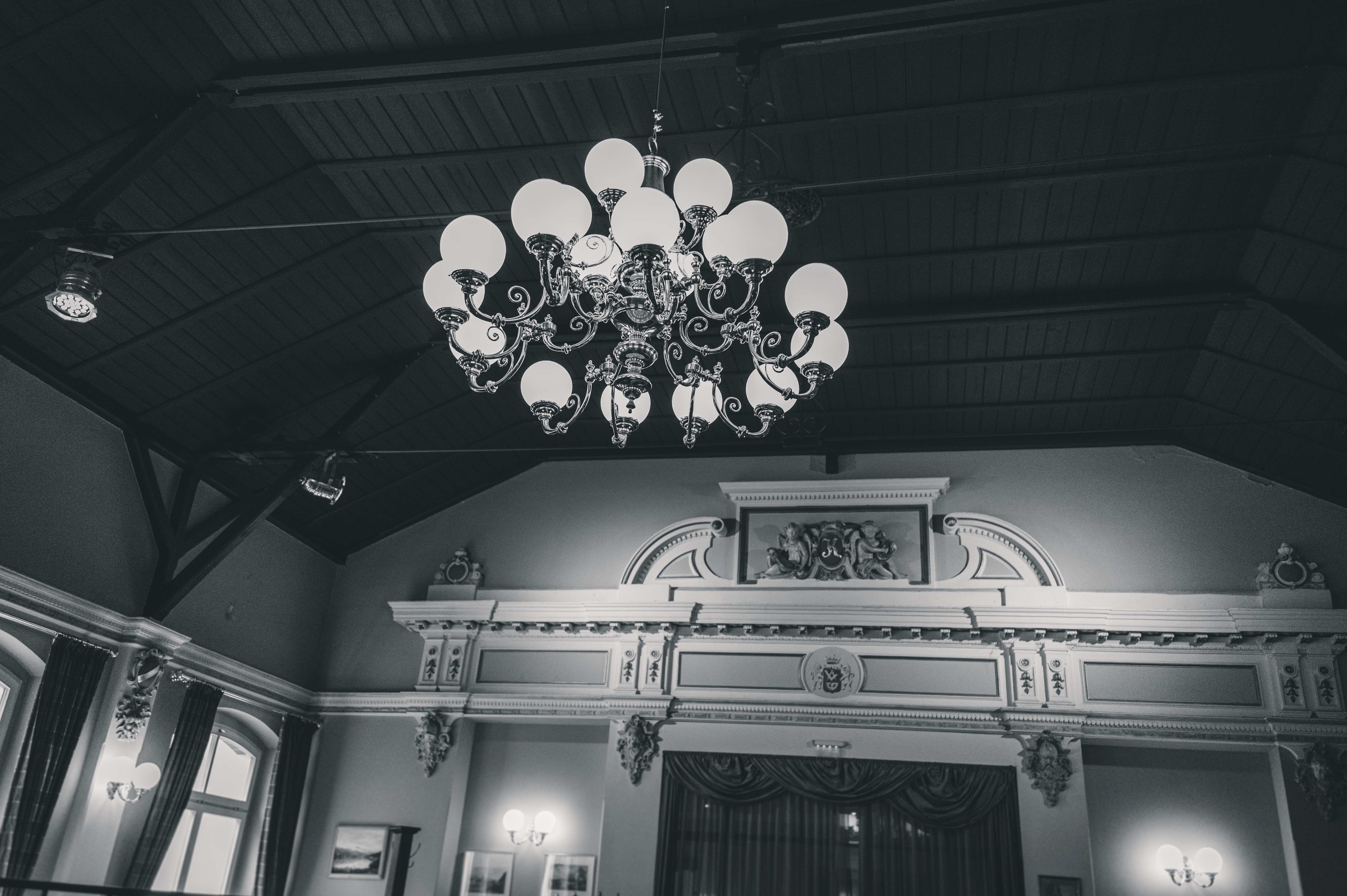 Eine stimmungsvolle Schwarz-Weiß-Aufnahme des großen, prunkvollen Kronleuchters und der verzierten Holzdecke im Festsaal bei Dresden.