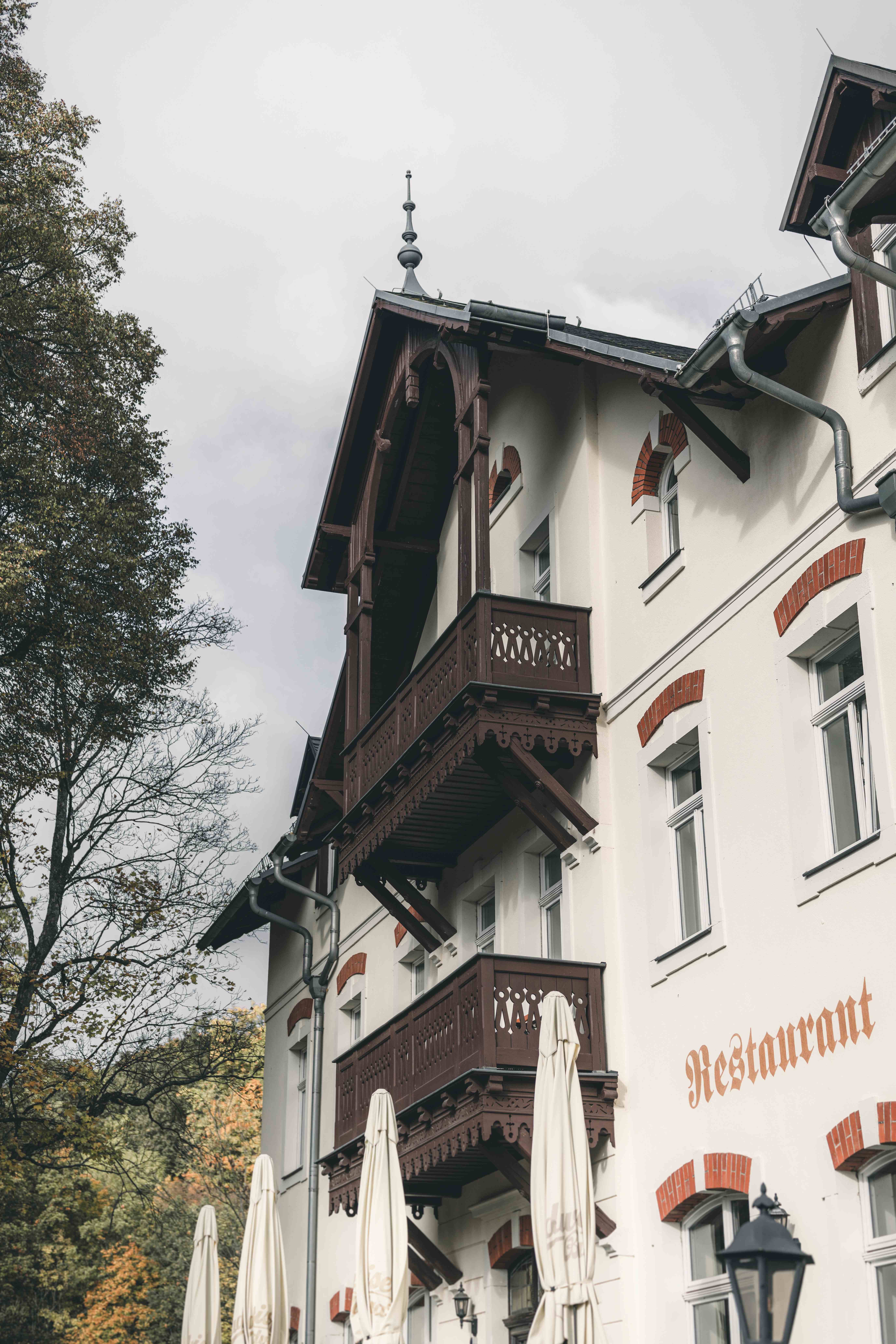 Nahaufnahme der charakteristischen Fassade der Spitzgrundmühle in Coswig mit den verzierten Holz-Balkonen und dem aufgemalten Restaurant-Schriftzug.