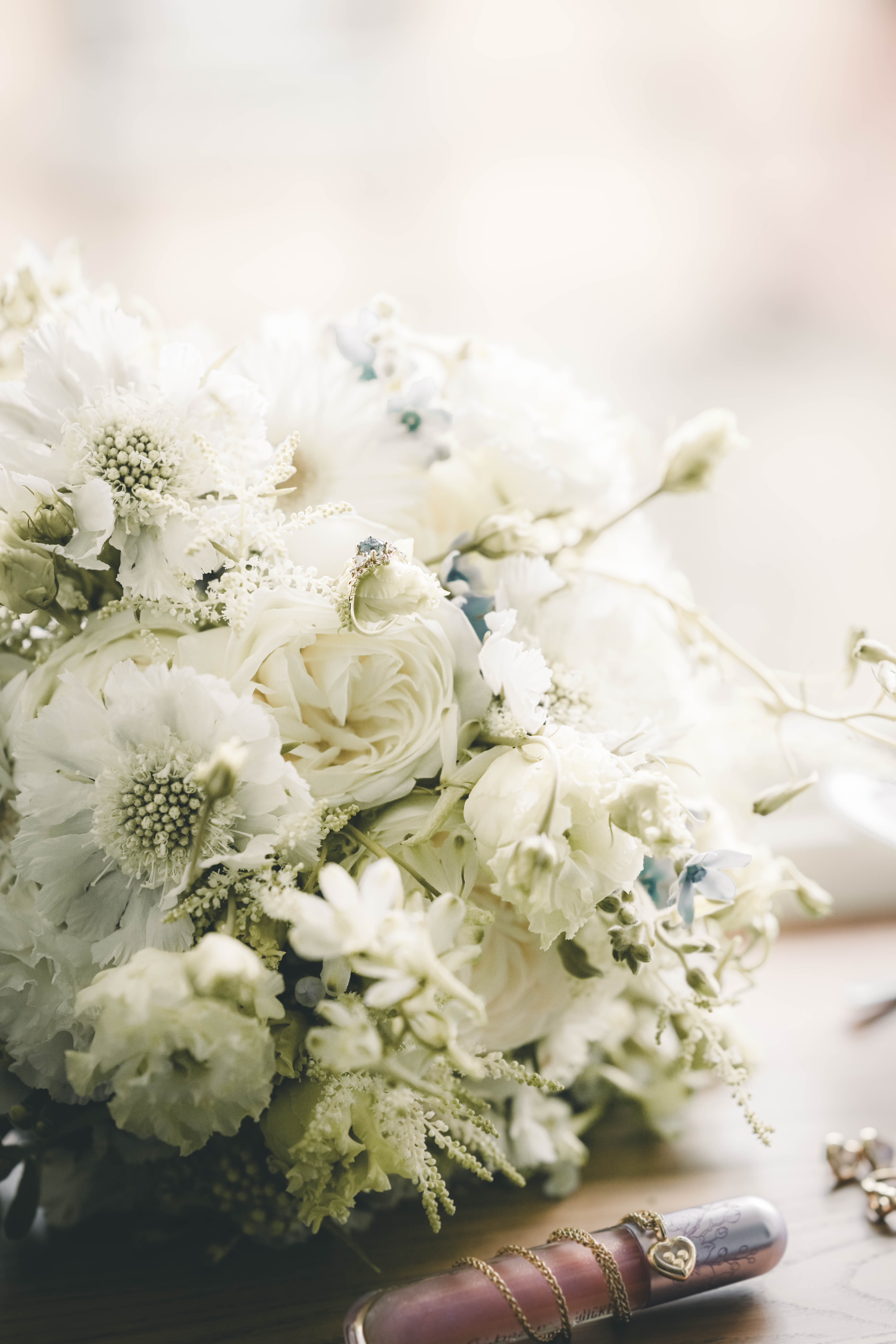 Detailaufnahme eines weißen Brautstraußes aus Rosen und Skabiosen mit einem filigranen Ring zwischen den Blütenblättern im Magdalenengut Erfurt.