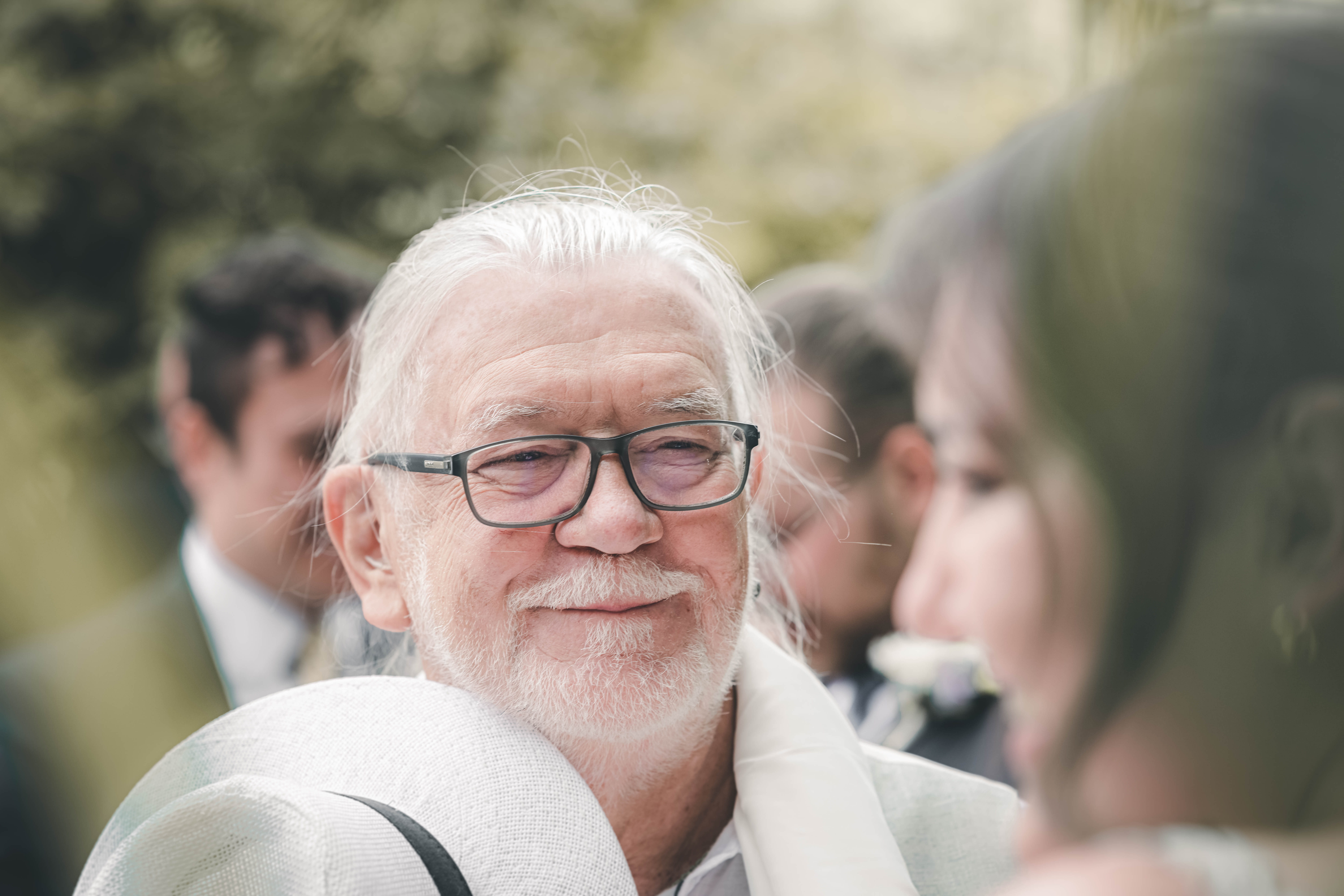 Ein älterer Herr mit weißem Bart, Brille und Strohhut blickt die Braut bei den Glückwünschen im Magdalenengut Erfurt liebevoll an.