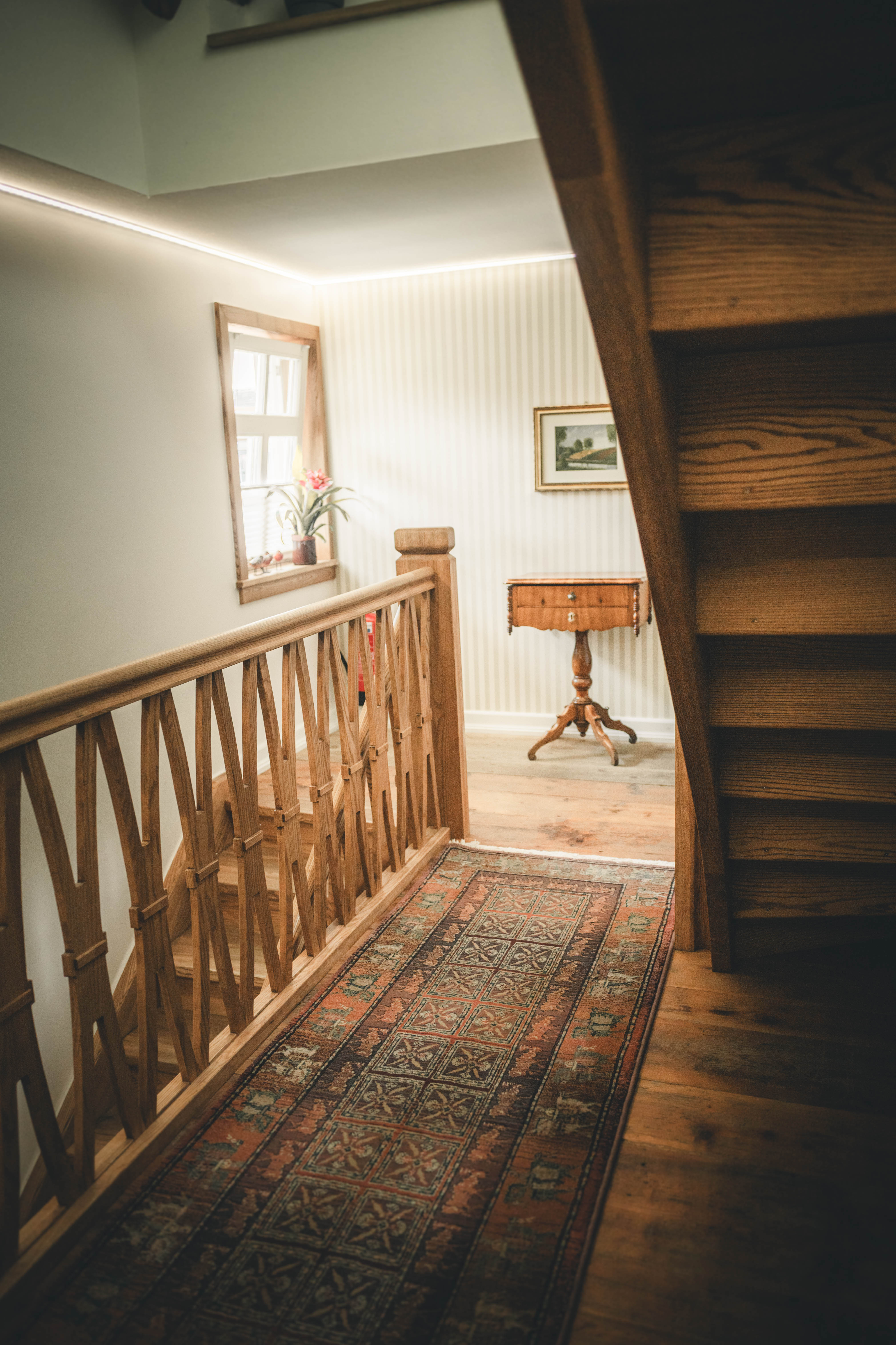 Innenbereich im Magdalenengut Erfurt mit Holztreppe, traditionellem Holzgeländer, Orientteppich und antikem Beistelltisch.