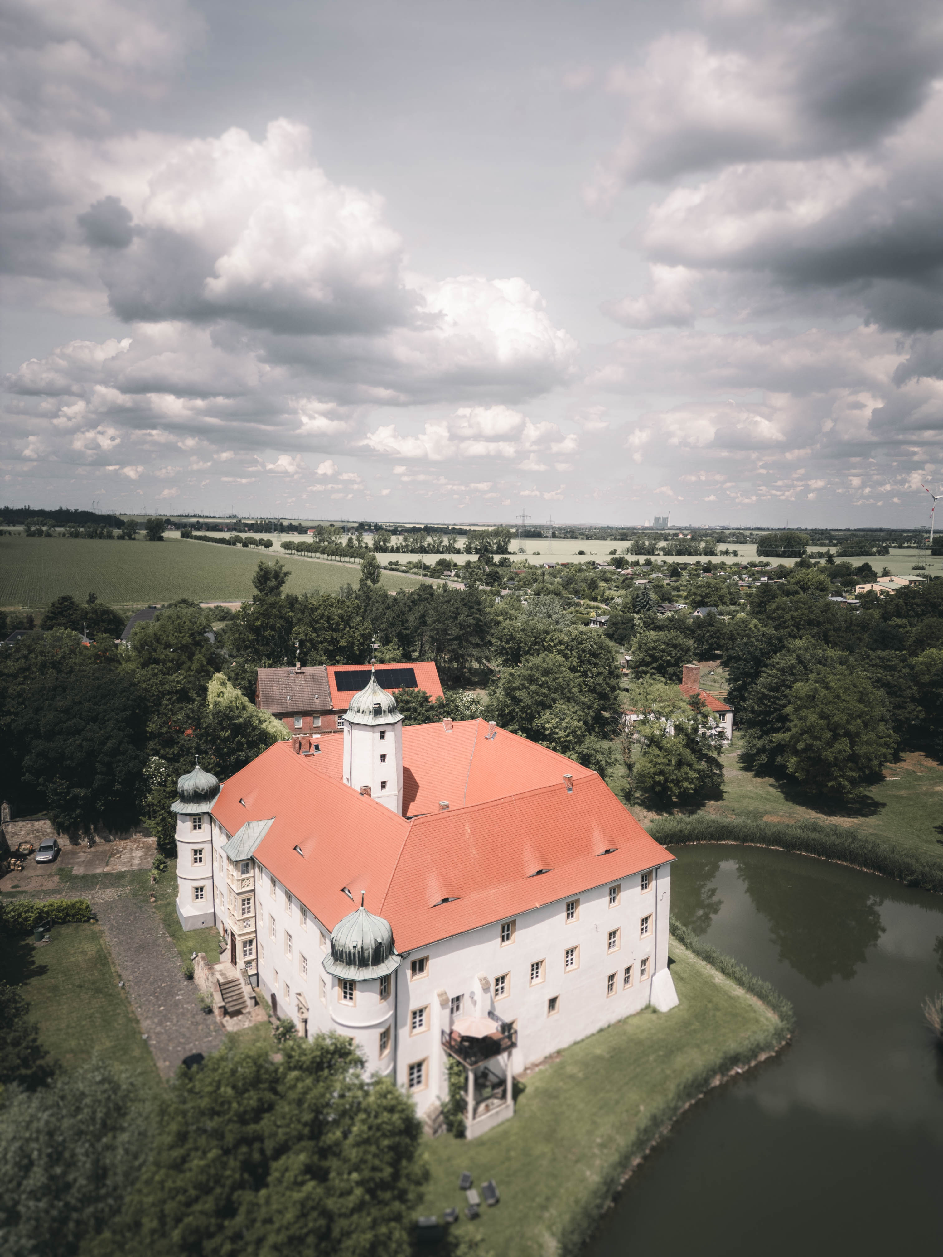 Eine beeindruckende Drohnen-Luftaufnahme des Wasserschlosses Frankleben mit seinem markanten roten Dach und dem schützenden Wassergraben im Saalekreis.