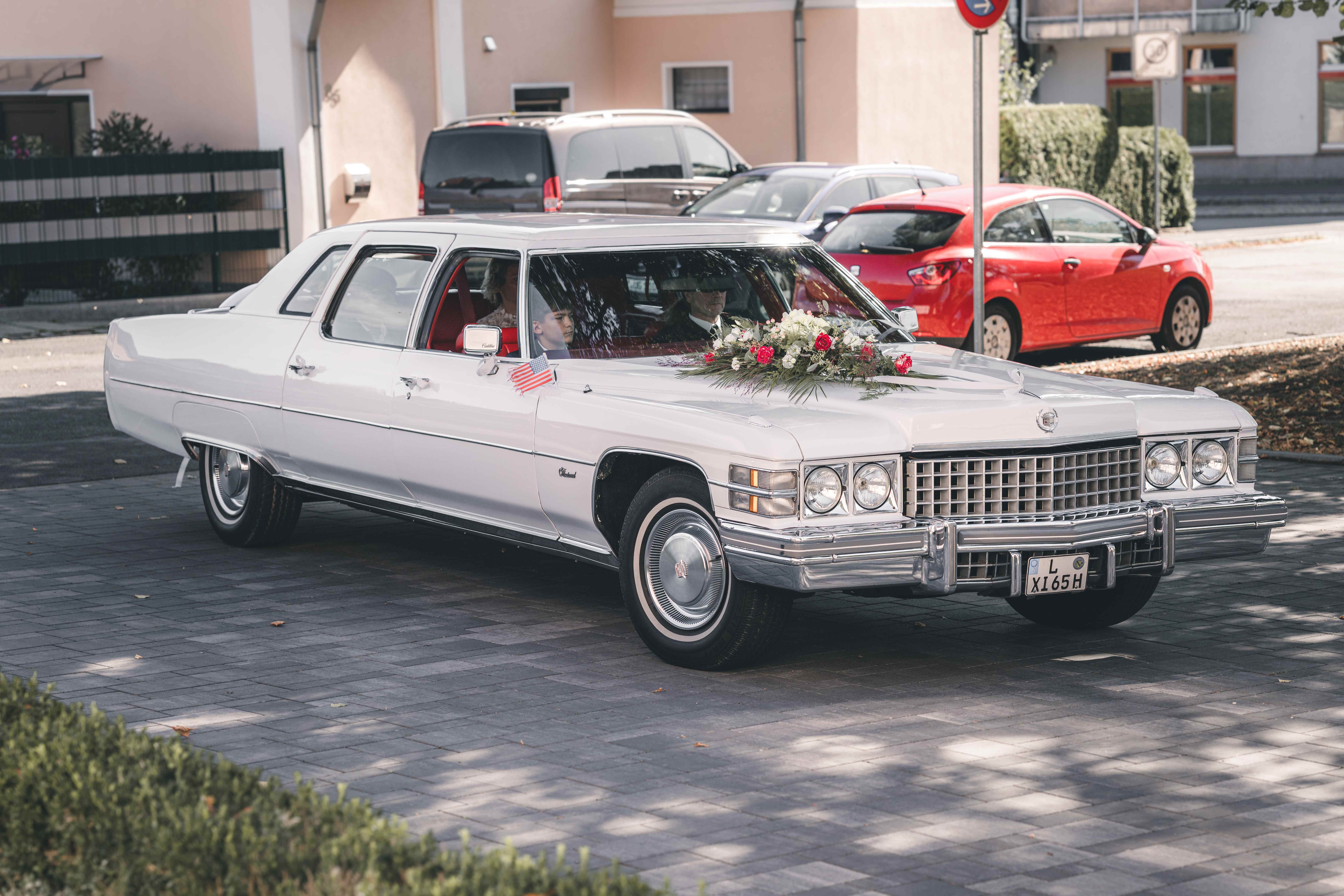 Ein weißer Cadillac-Oldtimer mit floralem Raumschmuck fährt auf dem Vorplatz des Standesamts in Fraureuth vor.