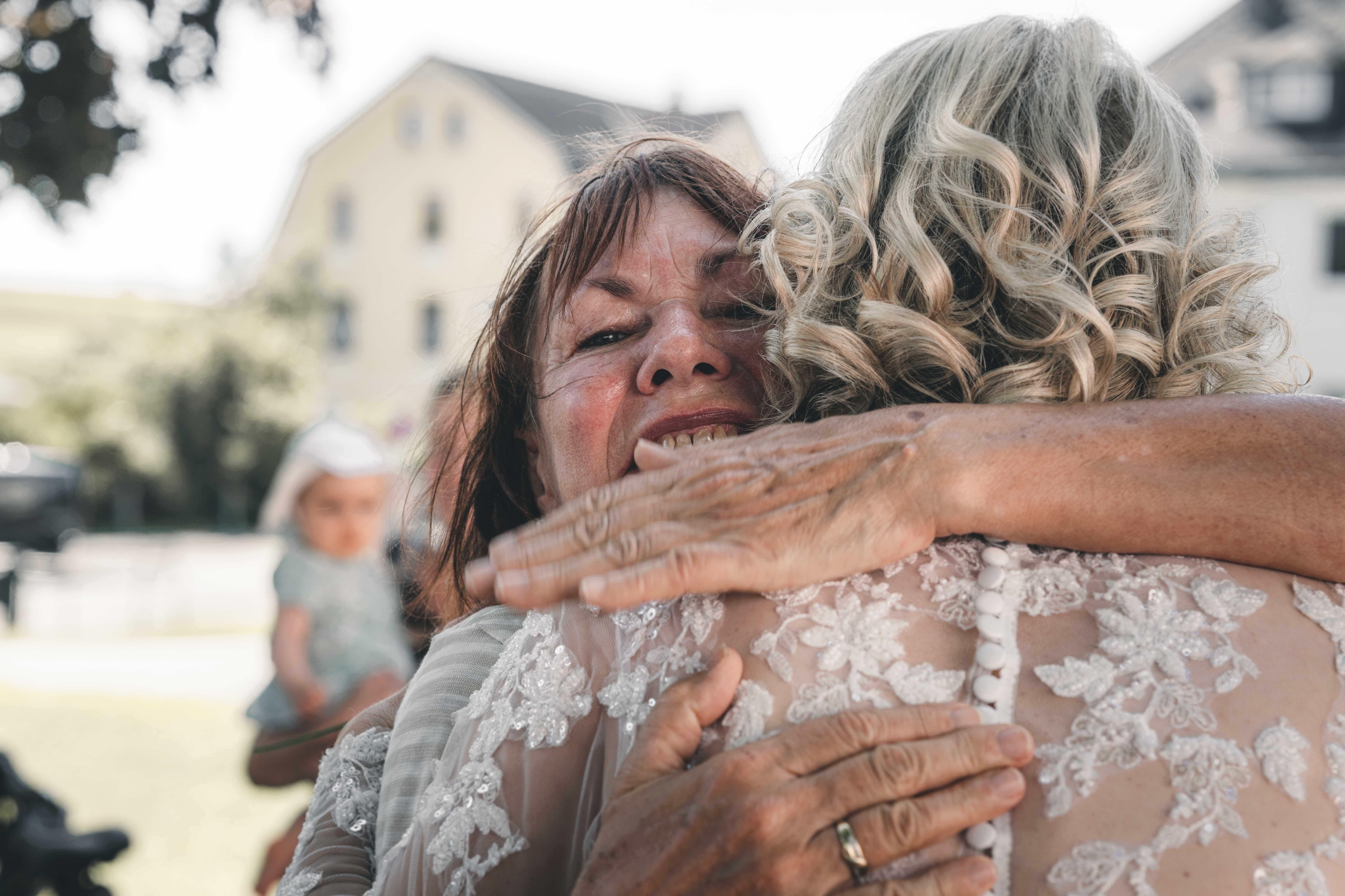 Eine überglückliche ältere Gästin drückt die Braut nach der Trauung in Sachsen ganz fest an sich, Tränen der Rührung in den Augen.