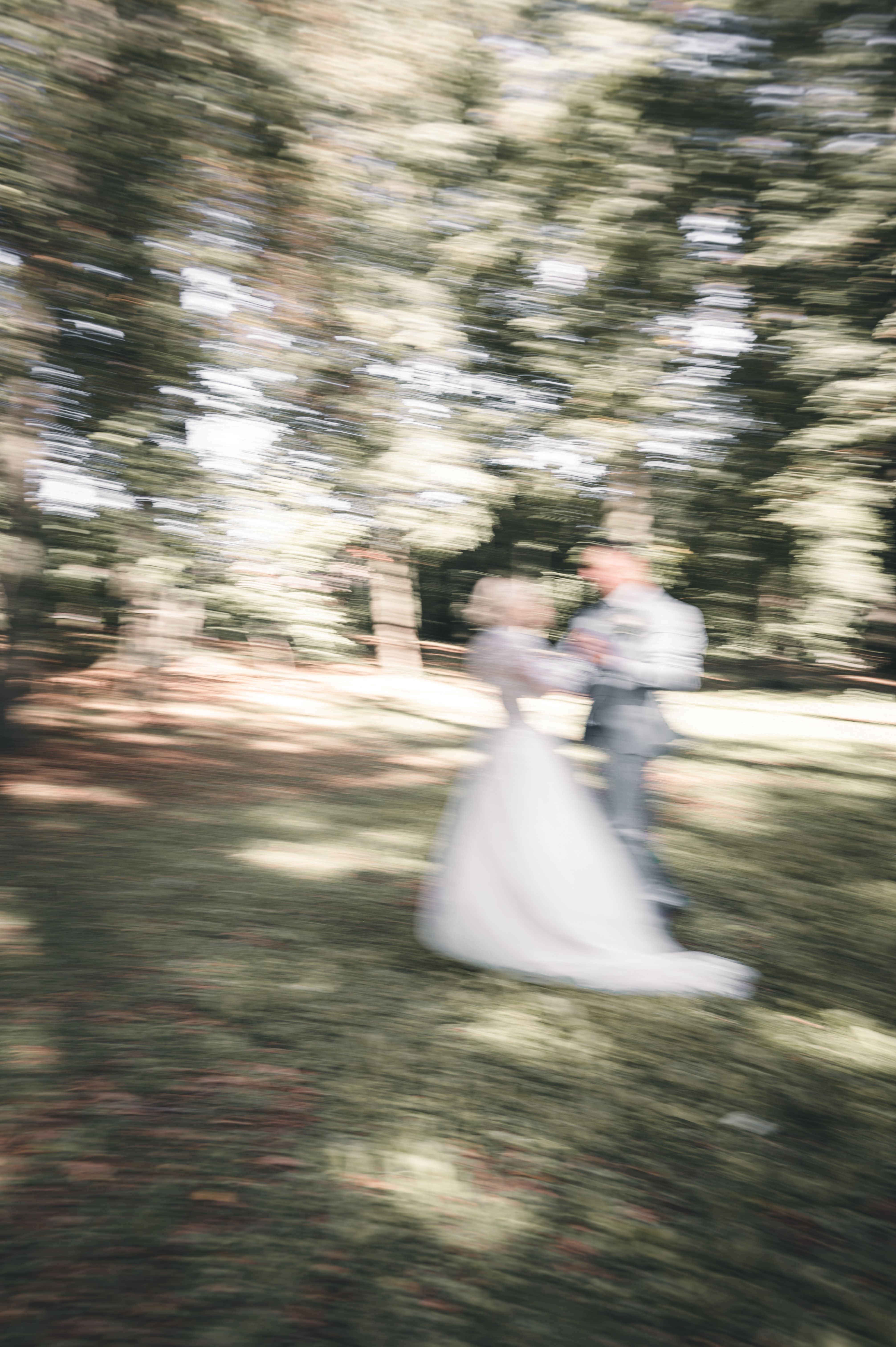 Ein kreatives Hochzeitsfoto mit gewollter Bewegungsunschärfe (Motion Blur) zeigt das Brautpaar beim Tanzen auf einer Waldlichtung im Erzgebirge.