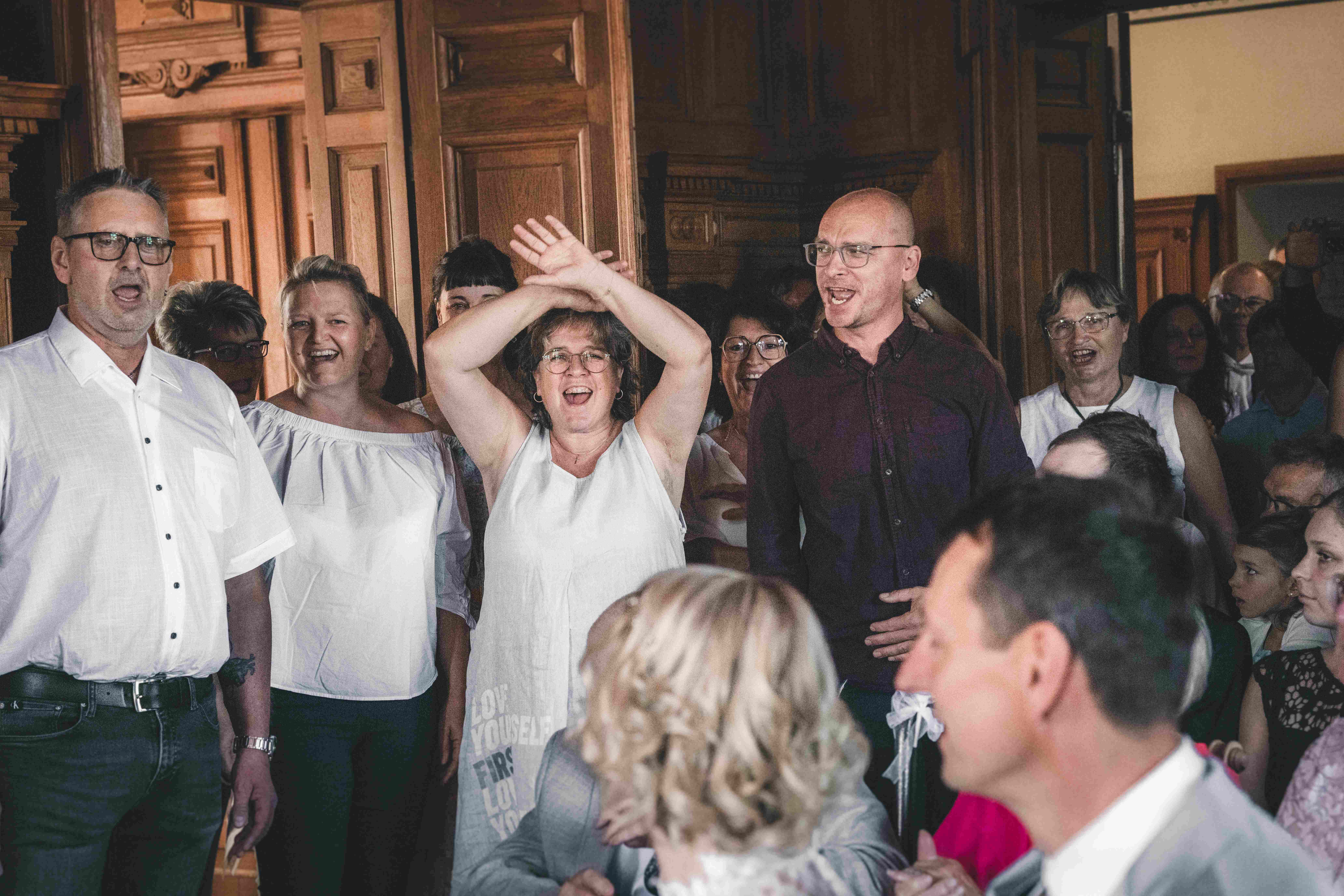 Die Hochzeitsgesellschaft singt während der standesamtlichen Trauung im Rathaus Fraureuth emotional und klatscht für das Brautpaar.