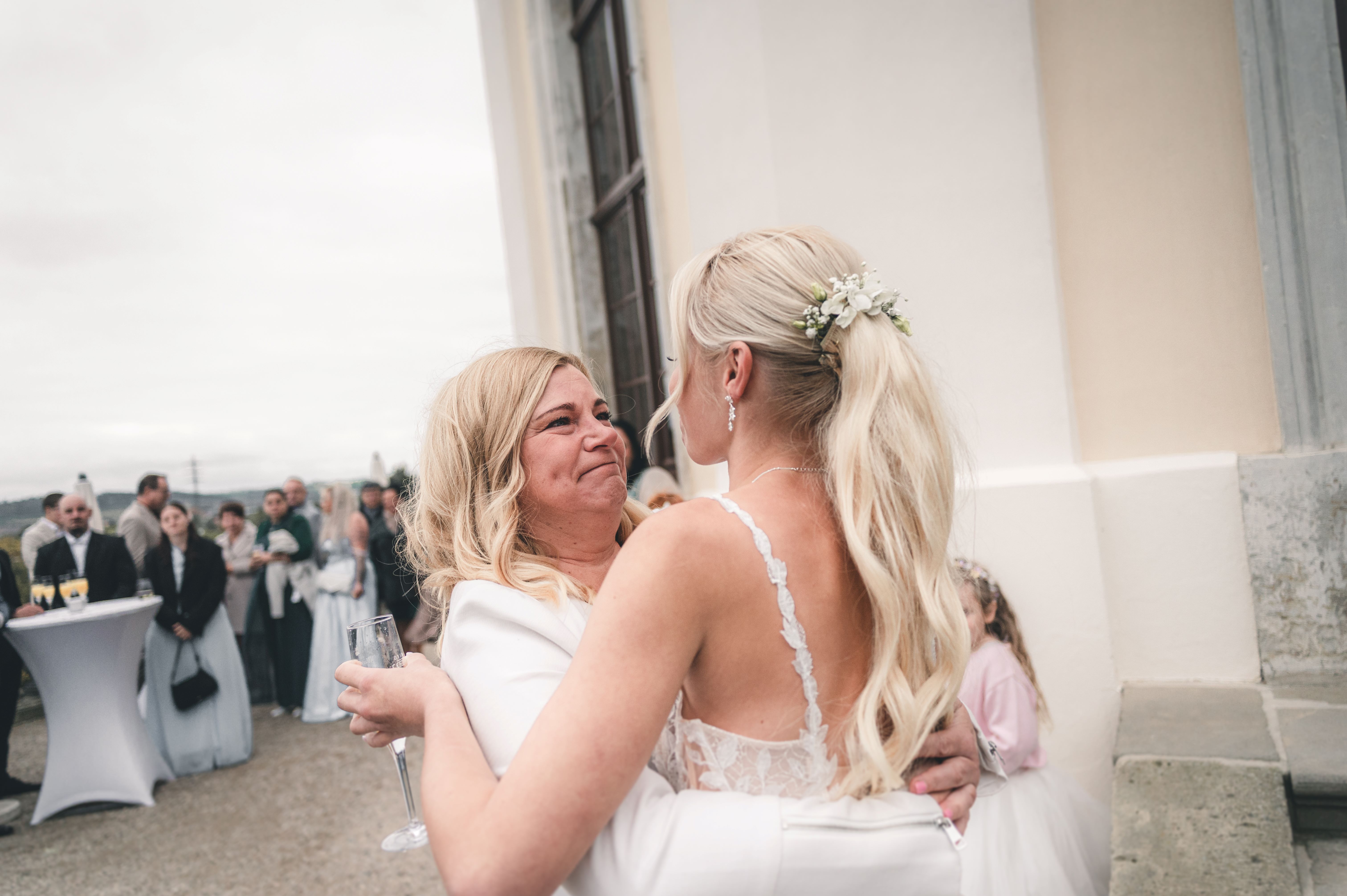 Eine Gästin weint vor Glück, während sie die frischgebackene Braut auf der Terrasse von Schloss Wackerbarth fest an sich drückt.