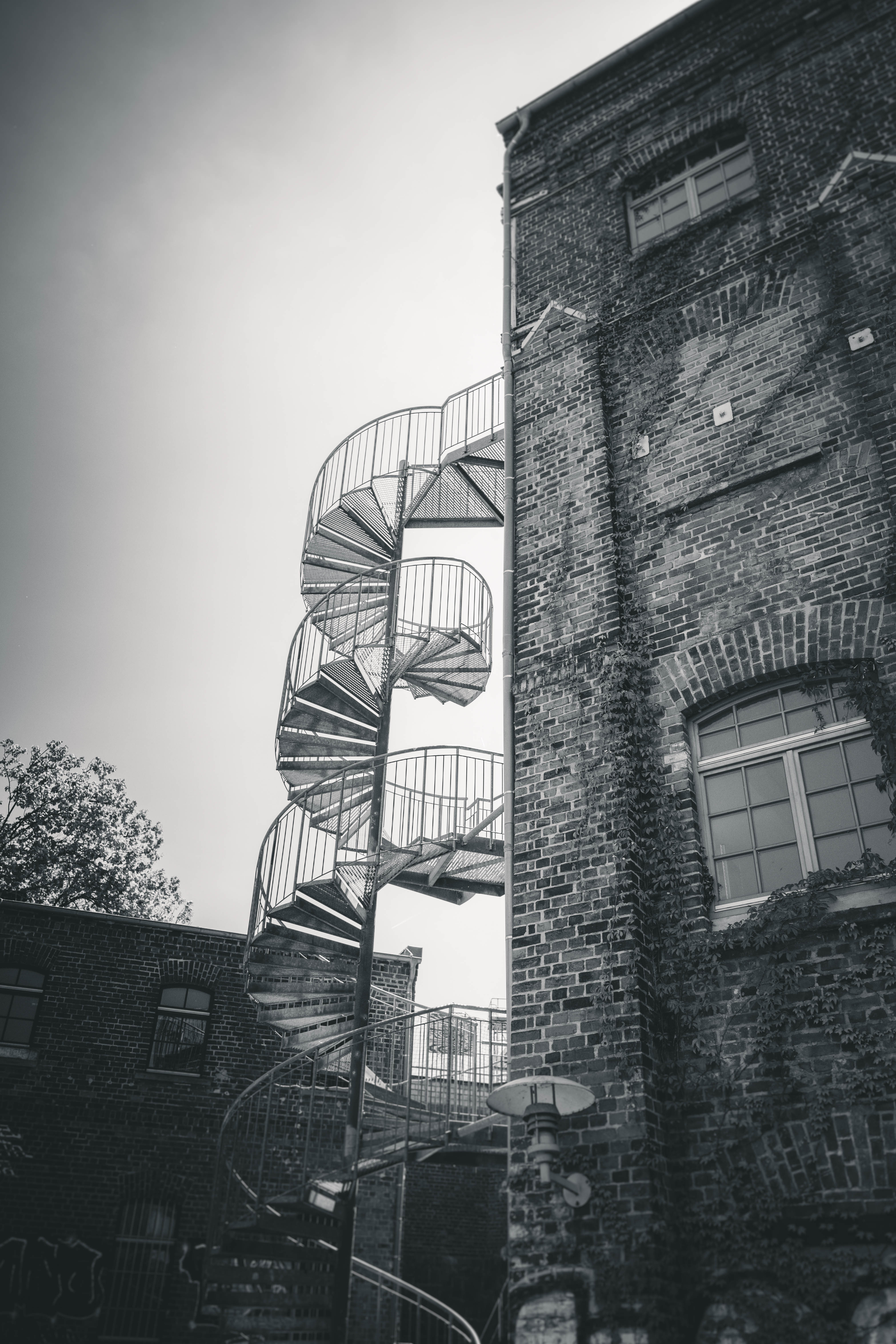 Eine kontrastreiche Schwarz-Weiß-Aufnahme des historischen Klinkerbaus vom Mörtelwerk Leipzig mit einer markanten Metall-Wendeltreppe.